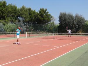 2 personnes jouant au tennis sur un court dans l'établissement Village Vacances de Ramatuelle - Les sentier des pins, à Saint-Tropez
