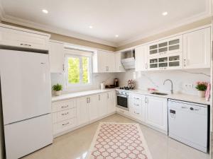 a white kitchen with white cabinets and a sink at Apart Portakal Çiçeği in Kaş