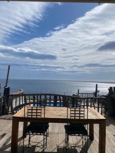 a wooden table and chairs on a deck overlooking the ocean at ALICIA in Zonza