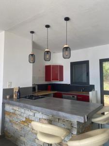 a kitchen with a stone counter with chairs and lights at ALICIA in Zonza +9 photos