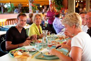 un groupe de personnes assises à une table en train de manger dans l'établissement Village Vacances de Ramatuelle - Le Sentier des Pins, à Saint-Tropez