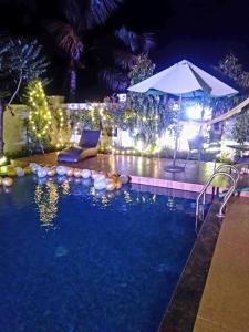 a swimming pool at night with an umbrella at WayFare Stud Farm & Resort in Nashik