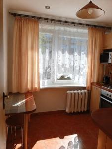 a kitchen with a window with curtains and a table at Komfortowy Apartament na wyłączność 2 Sypialnie Blisko Centrum in Gorlice +2 photos