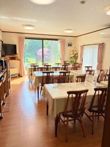 a restaurant with tables and chairs and a large window at Yabukiso in Yamanakako