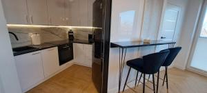 a kitchen with a black refrigerator and two bar stools at Wschód Słońca Ełk in Ełk
