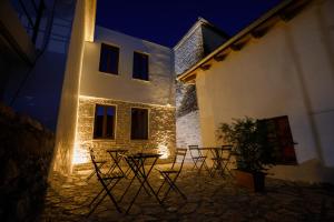 a group of tables and chairs in front of a building at night at Old Street Villa in Gjirokastër