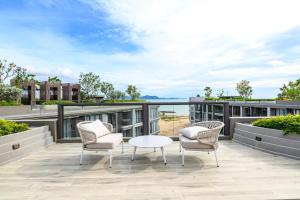a patio with chairs and a table on a roof at Beachfront 1BDR Condo (PE24) in Na Jomtien