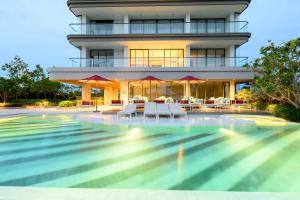 a house with a swimming pool in front of a building at Beachfront 1BDR Condo (PE24) in Na Jomtien