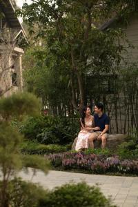 a man and woman sitting on a rock in a garden at Rivana Retreat in Sóc Sơn +36 photos
