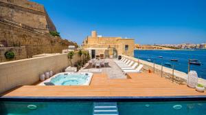 a hot tub on a deck next to the water at Valletta Waterfront Villa with Pool and Jacuzzi in Valletta