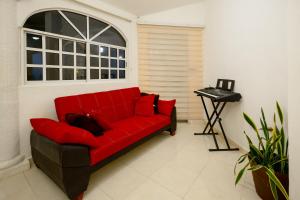 a red couch in a room with a window at Departamento 1 Hab con Alberca, Gym y Terraza in Mérida