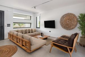 a living room with two couches and a tv at Palmeral Luxury Villas in Kremasti