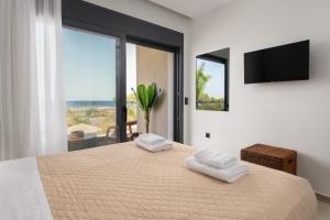 a bedroom with a bed with two towels on it at Palmeral Luxury Villas in Kremasti +35 photos
