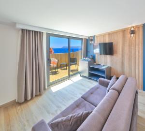 a living room with a couch and a desk and a television at Kas Athena Hotel in Kaş