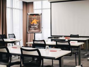 a classroom with tables and chairs and a screen at Ibis Rouen Centre Rive Gauche Mermoz in Rouen