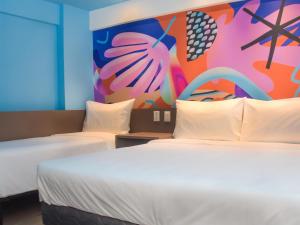 a room with two beds and a colorful wall at Ibis Styles Garanhuns in Garanhuns