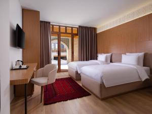 a bedroom with two beds and a desk and a television at Mercure Bukhara Old Town in Bukhara +65 photos
