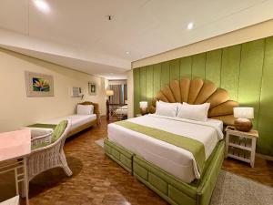 ein Hotelzimmer mit zwei Betten und einem Tisch in der Unterkunft Coco Grande Hotel in Dumaguete