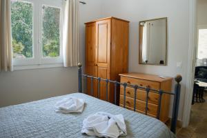 a bedroom with a bed and a dresser and a mirror at Charmante petite maison à Corfou in Pelekas
