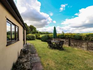 a patio with a table and chairs and a umbrella at Ryecross Farm Cottage in Melbury Abbas