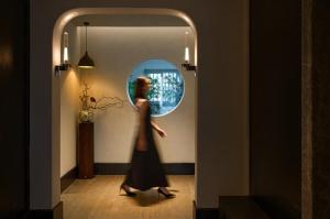 a woman walking through a hallway with a round window at Chengdu Yunduo Bieyuan 云朵 Hotel in Chengdu