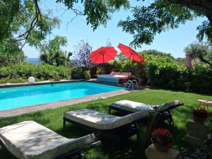 a swimming pool with two red umbrellas in a yard at Le jardin de Sabine in Éguilles