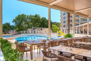 a restaurant with tables and chairs and a swimming pool at GRIFID Arabella Hotel - Ultra All inclusive & Aquapark in Golden Sands