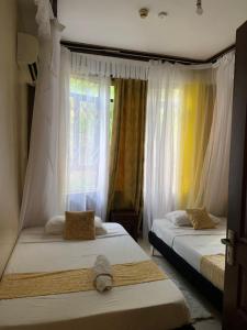 two beds in a room with a window at Amboseli 2 in Mombasa