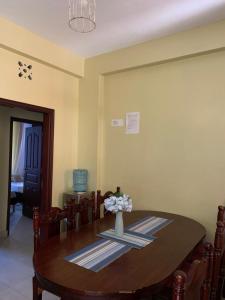 a dining room table with a vase of flowers on it at Amboseli 2 in Mombasa