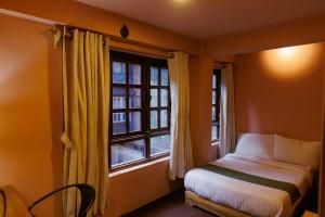 a small bedroom with a bed and a window at Manju Baha Hotel in Bhaktapur
