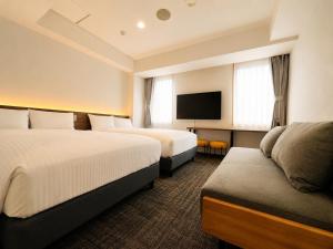 a hotel room with two beds and a flat screen tv at ホテル翔 Sapporo PARKSIDE HOTEL in Sapporo