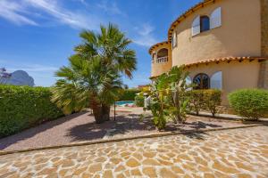 a house with a palm tree next to a building at Villa Ortembach- PlusHolidays in Ifach