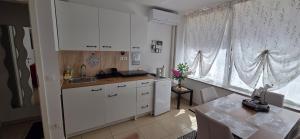 a kitchen with white cabinets and a table in front of a window at Apartments Violeta in Bled