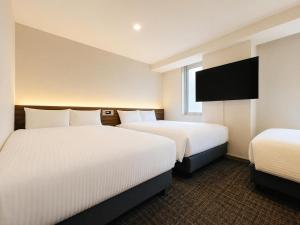 a hotel room with two beds and a flat screen tv at ホテル翔 Sapporo PARKSIDE HOTEL in Sapporo