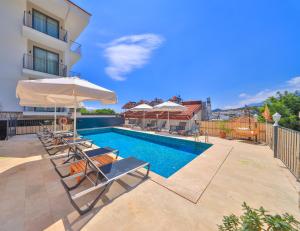 a swimming pool with chairs and umbrellas next to a building at Kas Athena Hotel in Kaş