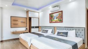 two beds in a room with white walls at Phượng Sơn Hotell in Sầm Sơn +4 photos