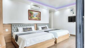 two beds in a hotel room with a tv at Phượng Sơn Hotell in Sầm Sơn