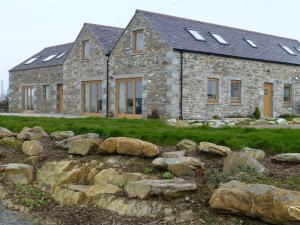 una casa de piedra con ventanas y rocas delante de ella en Cairndoon Byre en Monreith