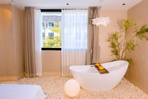a bathroom with a large white tub in front of a window at UMEE Homestay in Thôn Trường Giang