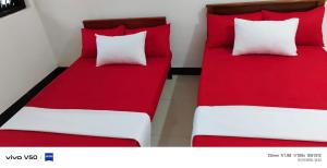 two beds with red and white pillows in a room at Elite moon hotel in Kallady