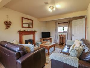 a living room with leather furniture and a television at Barclay Cottage in Ashford