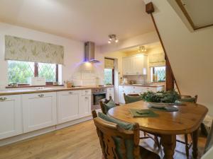 a kitchen with a wooden table and a dining room at Barclay Cottage in Ashford