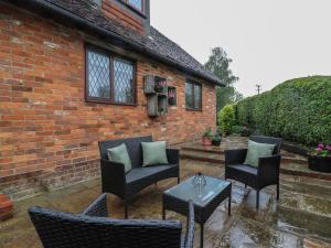 a patio with chairs and a table and a brick building at Barclay Cottage in Ashford