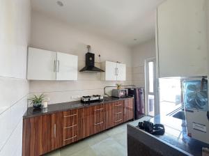 a kitchen with wooden cabinets and white appliances at Red Brick House in Panchkula +12 photos