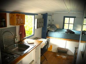 a kitchen with a sink and a bed in a tiny house at Roulotte nature in Salernes