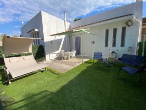 a yard with a bench and chairs in front of a house at Vento a poppa in Porto Palo