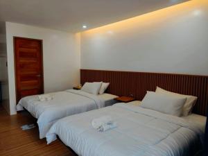 two beds in a hotel room with white sheets at The Annwin Hotel - Sablayan in Sablayan