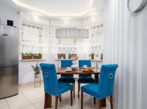 a kitchen with a wooden table and blue chairs at Golden Villas Garden Retreat - Private Garden & BBQ in Kobyłka +25 photos