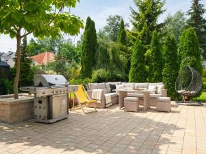 a patio with a grill and furniture in a yard at Golden Villas Garden Retreat - Private Garden & BBQ in Kobyłka