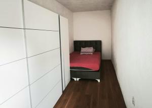 a small room with a bed with a red blanket at Spacious City Center Apartment for 6 - Steps from Hilton & Republic Square in Podgorica